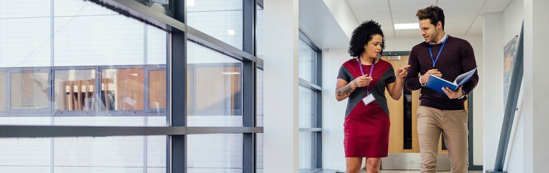 Two teachers walking through a hallway, discussing policies