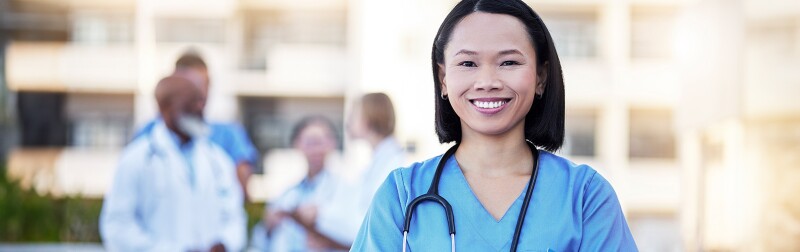 Nurse manager standing in front with her team behind her.