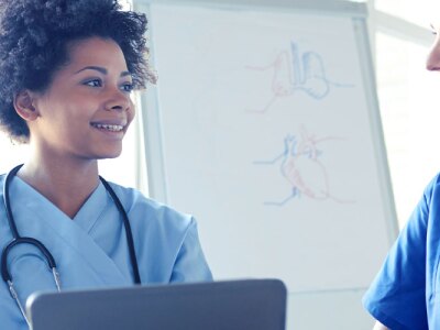 Female nurse with tablet discussing patient recommendations with nurse manager.