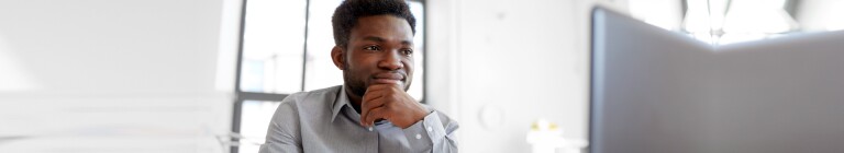 Young man sits in a room looking at a laptop