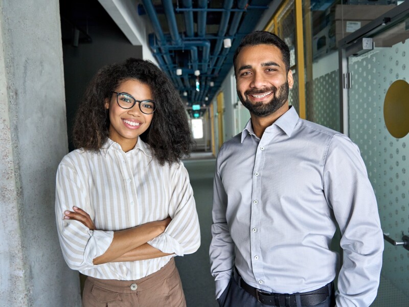 Two happy diverse professional business team people looking at camera in office.