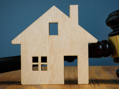 model of wooden home with a gavel behind