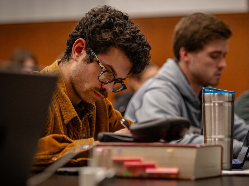 Male student taking notes in class.