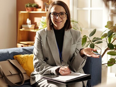 Social worker in suit sitting on sofa in the living room and talking to foster parents about custody at meeting at home
