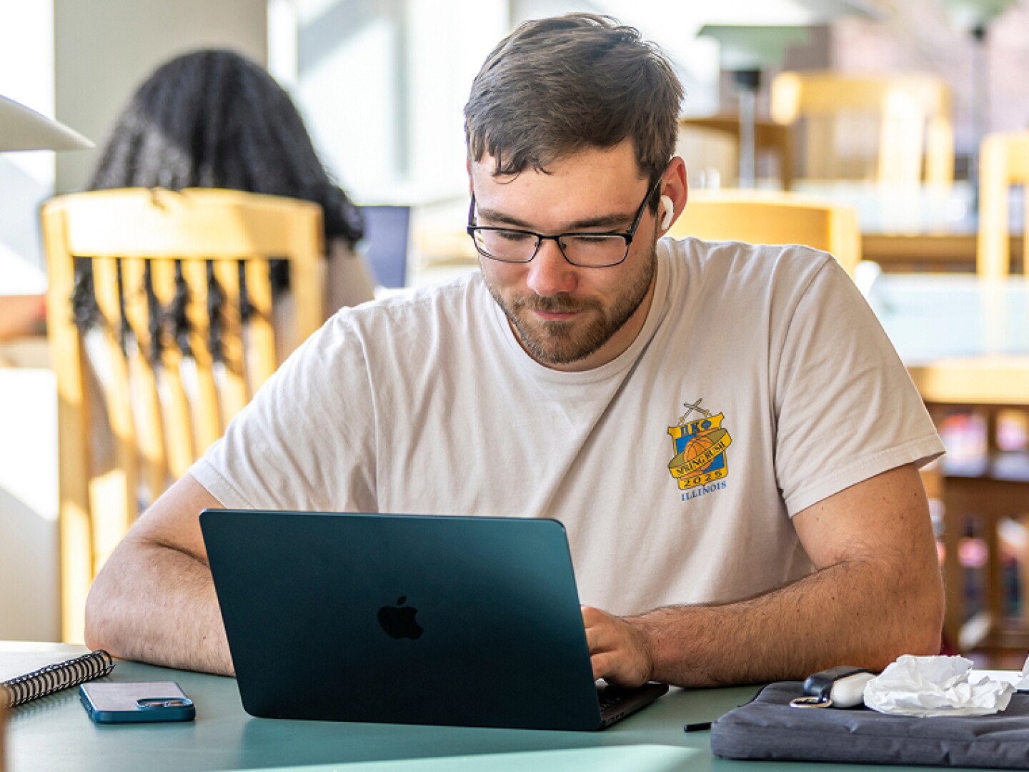 Man with glasses focused on his laptop.