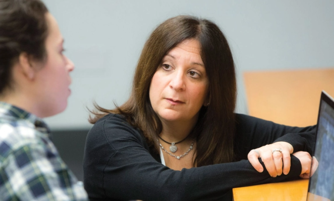 Woman listening intently to student speaking at desk
