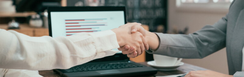 Close-up shot of two women shaking hands.