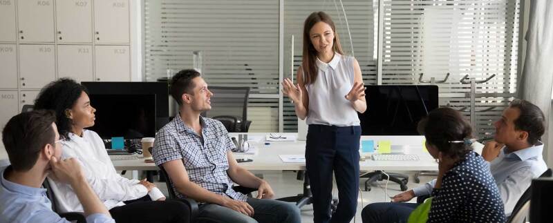 group sitting in office listening to woman in white shirt speaking