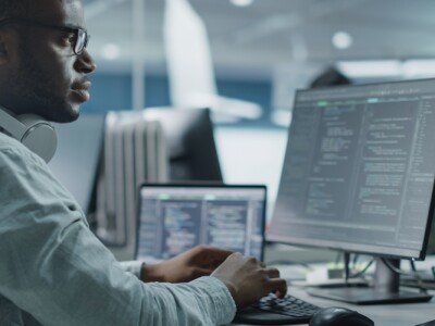 Male IT Programmer monitors security metrics at workstation computer.