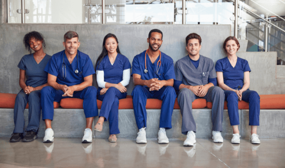 Six male and female nurses seated together across a bench