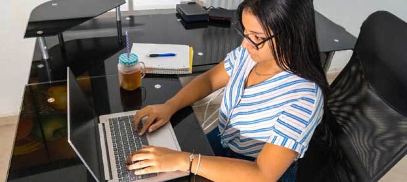 Woman in office setting works on a laptop