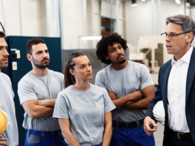professor standing in front of whiteboard speaking with 5 students