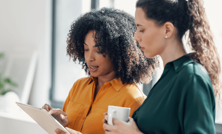Two woman talking while looking at tablet