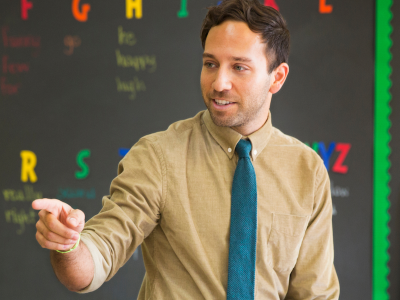 Male elementary school teacher standing in classroom