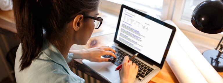 Young female blogger working at home.She sitting in her working room and typing something on laptop.