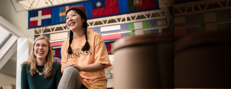 Marquette students laughing in front of international flags