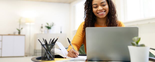 Woman sitting at desk, using computer researching how to get into an MBA program.