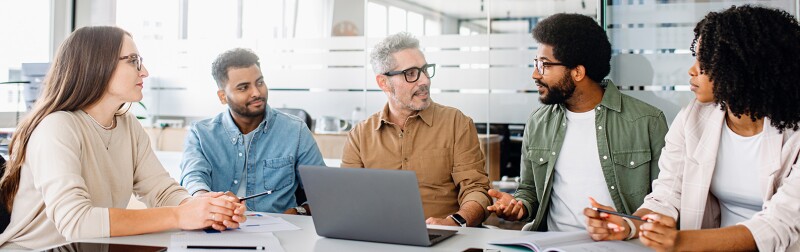 A team engaged in a strategic meeting, with a senior colleague leading discussion.