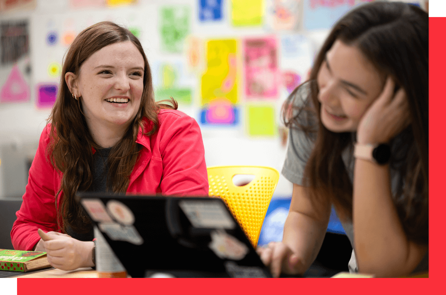Two women laughing together in front of laptop