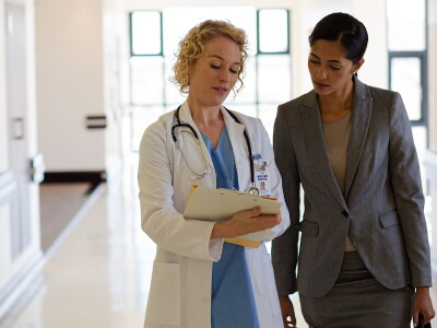 A doctor and hospital administrator walk together in a hospital corridor