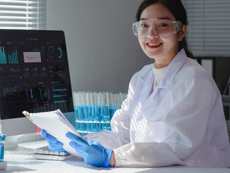 Epidemiologist analyzing data on computer and holding a report in a laboratory