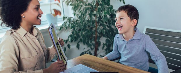 Teacher helping a smiling student learn the alphabet.
