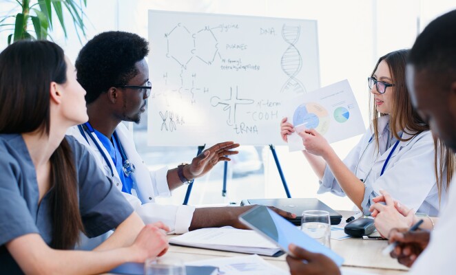 Female doctor holding in hands x ray result on the meeting at modern clinic.. Professional doctors of multi ethnic group examine x ray lungs of patient. Health care concept.
