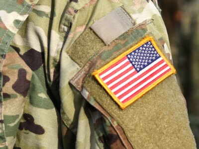 Close-up of an American soldier in uniform, standing in front of fellow soldiers.