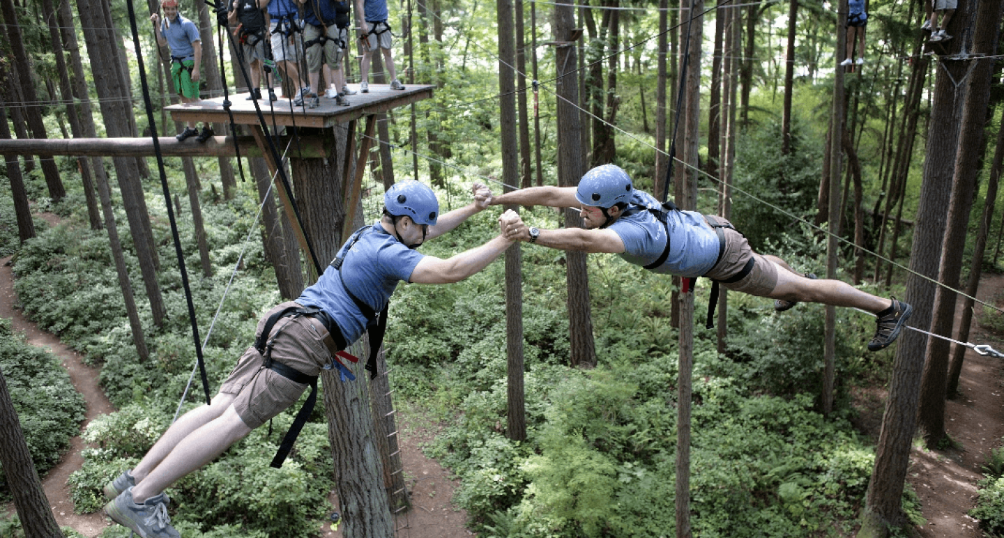 Two men on tightropes supporting holding each other up across a large space