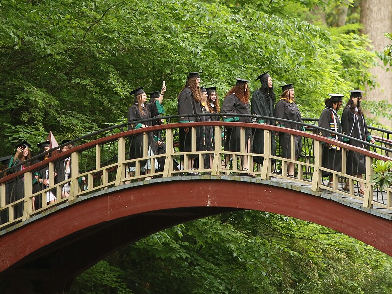 Graduates walking across the Crim Dell Bridge