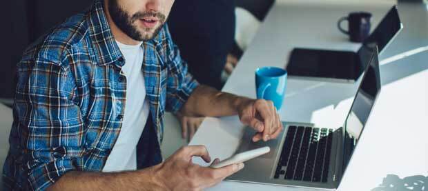 cybersecurity professional works on laptop and phone