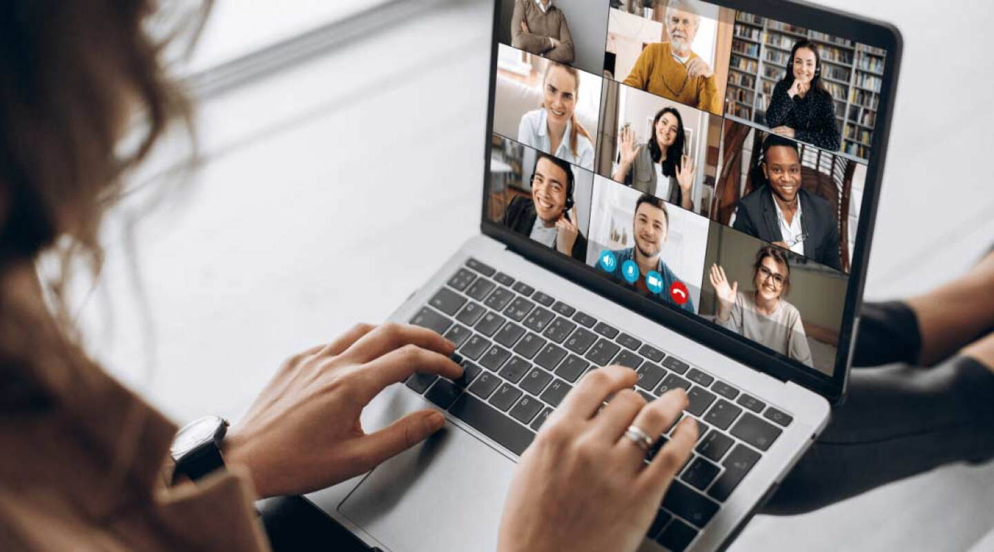Woman looking at laptop screen displaying meeting room participants