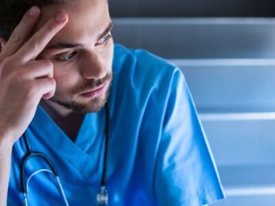 Tensed male nurse sitting on hospital staircase.