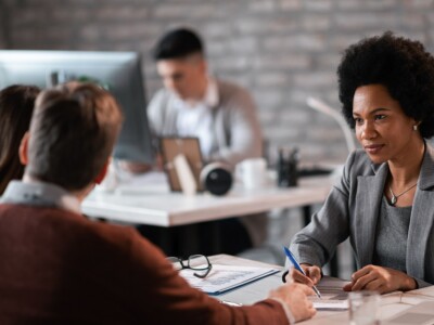 Woman in office takes notes as she actively listens to clients.