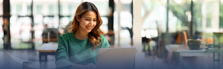 Woman in bright room looking at laptop and smiling