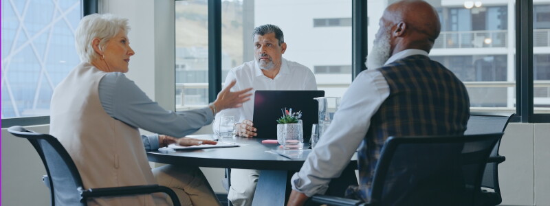 Three public health professionals in discussion around a table