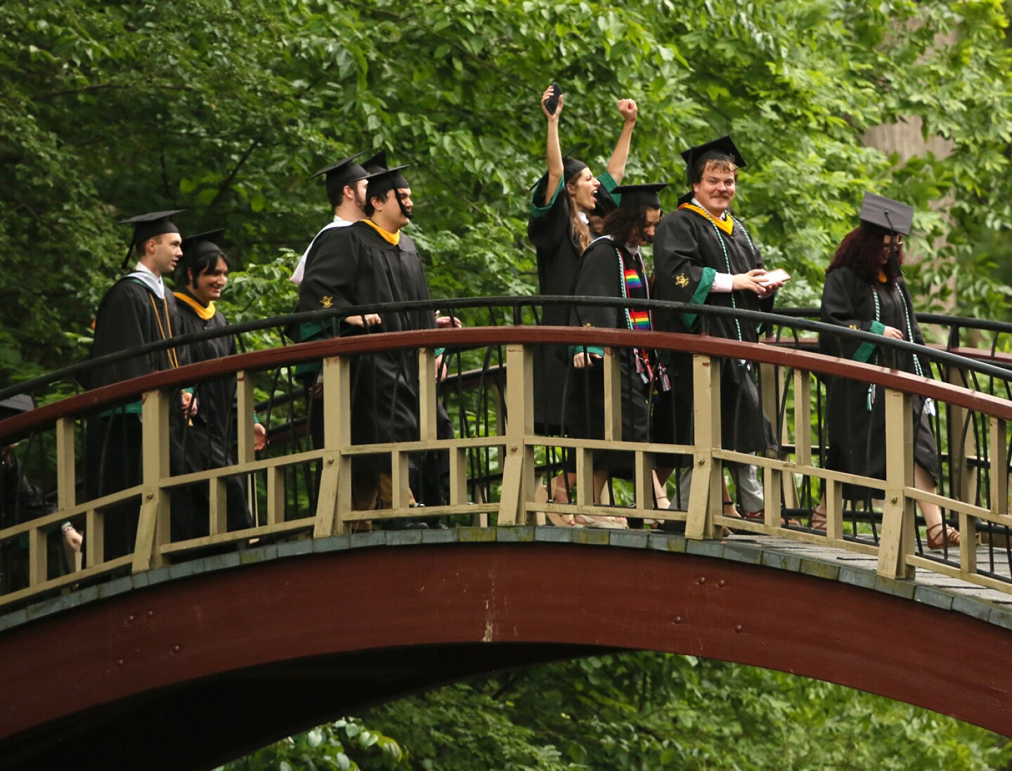 Graduates walk across the Crim Dell bridge