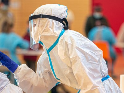 Health workers in protective suits are engaged in salivary and nasal tests inside a public gym.