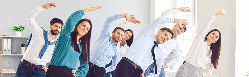 Office employees are participating in group stretching exercises as part of a workplace wellness program.