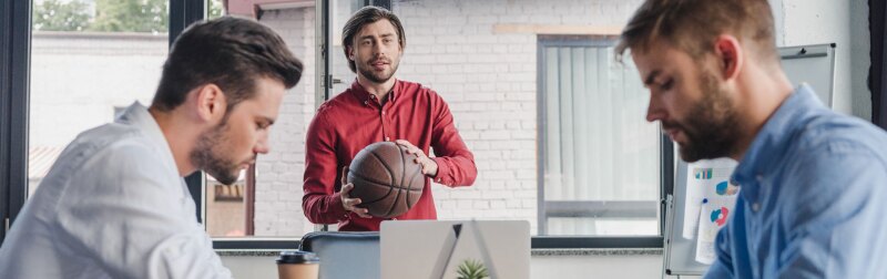 Young male sports manager discusses business strategies with male colleagues.