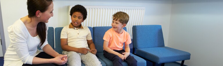 school counselor sitting down talking to two young boys