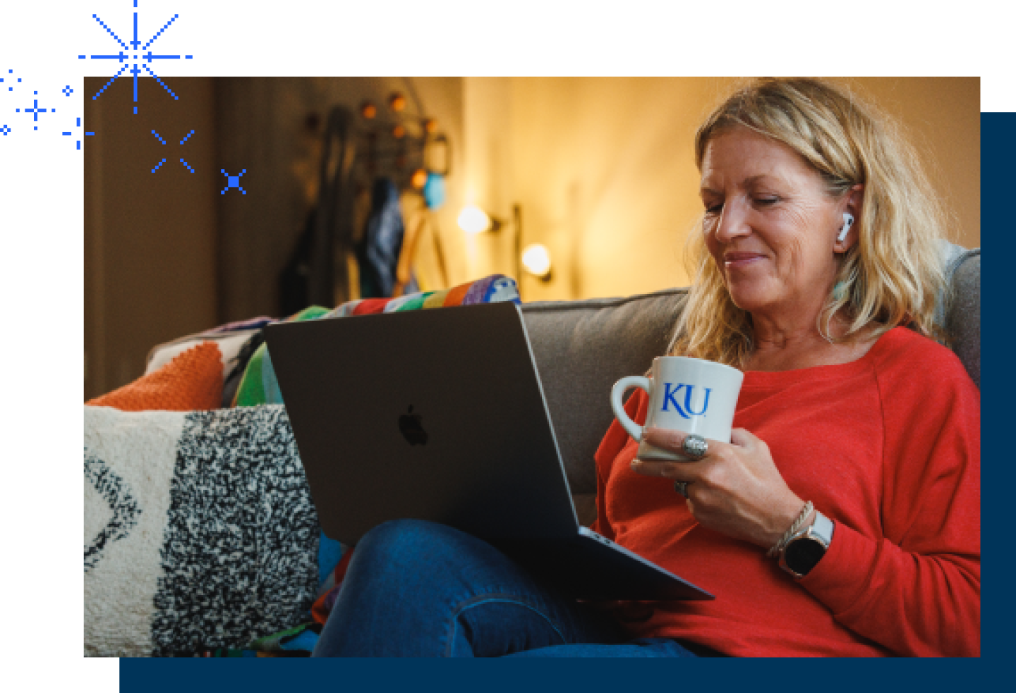 A middle-aged female KU student reviews her online lessons while sipping from a KU coffee mug.