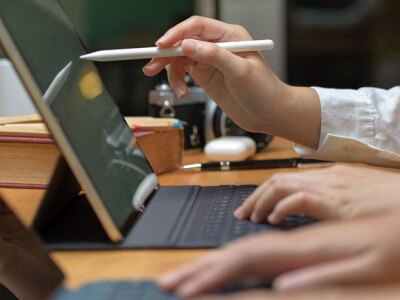 Two female workers consulting on their project while working with mock-up tablet on wooden table.