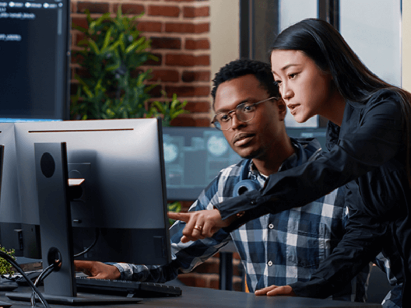 Seated man and standing woman at desktop computer