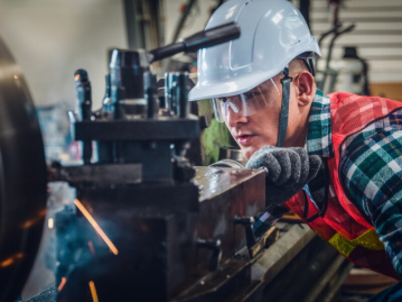 Close-up of a male mechanical engineer working a machine press for fabrication.