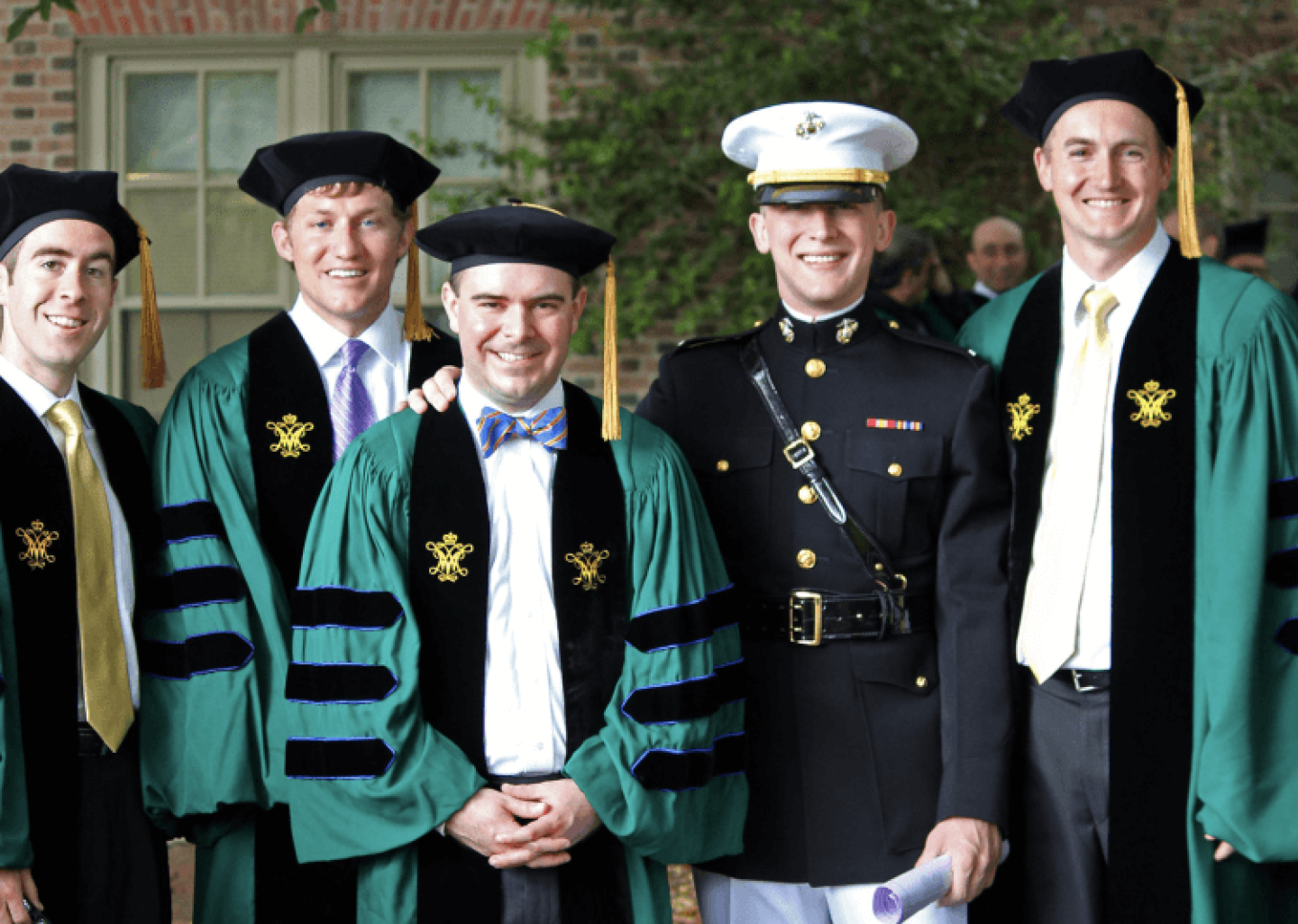 Group of William & Mary graduates in caps and gowns, one in Marines uniform