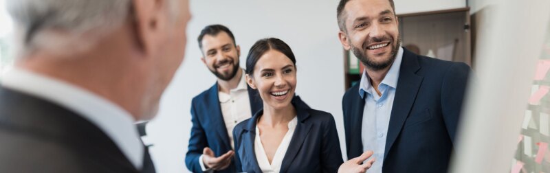 An Athletics Director and three employees review sports program schedule in office.