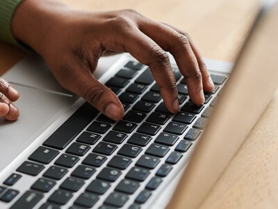 Hands of young black woman typing on laptop keyboard