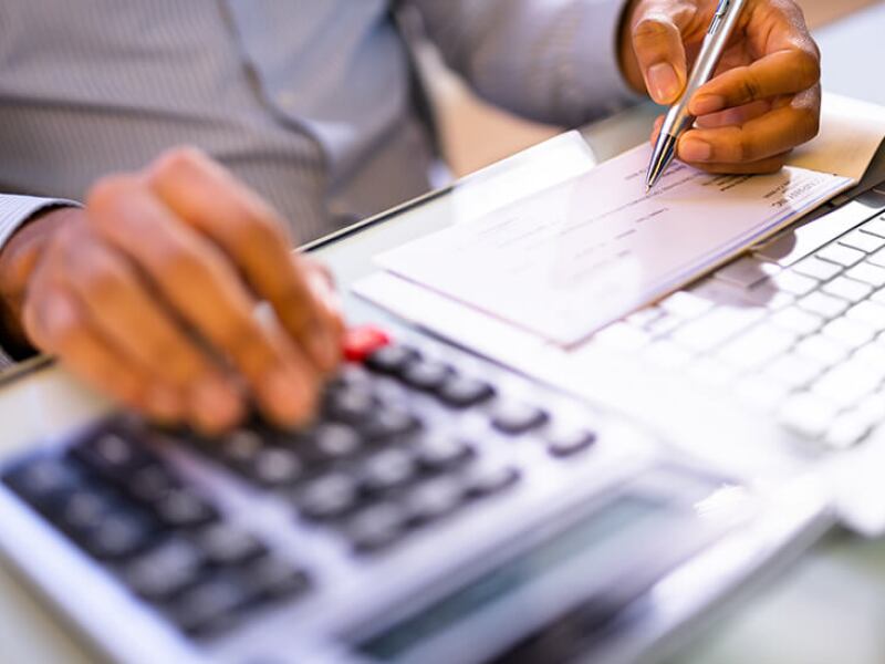 Hands using a calculator and writing a payroll check