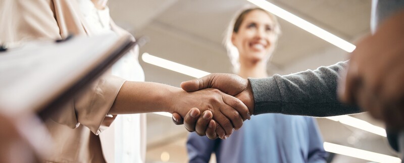 Close-up of co-workers handshaking after resolving a conflict